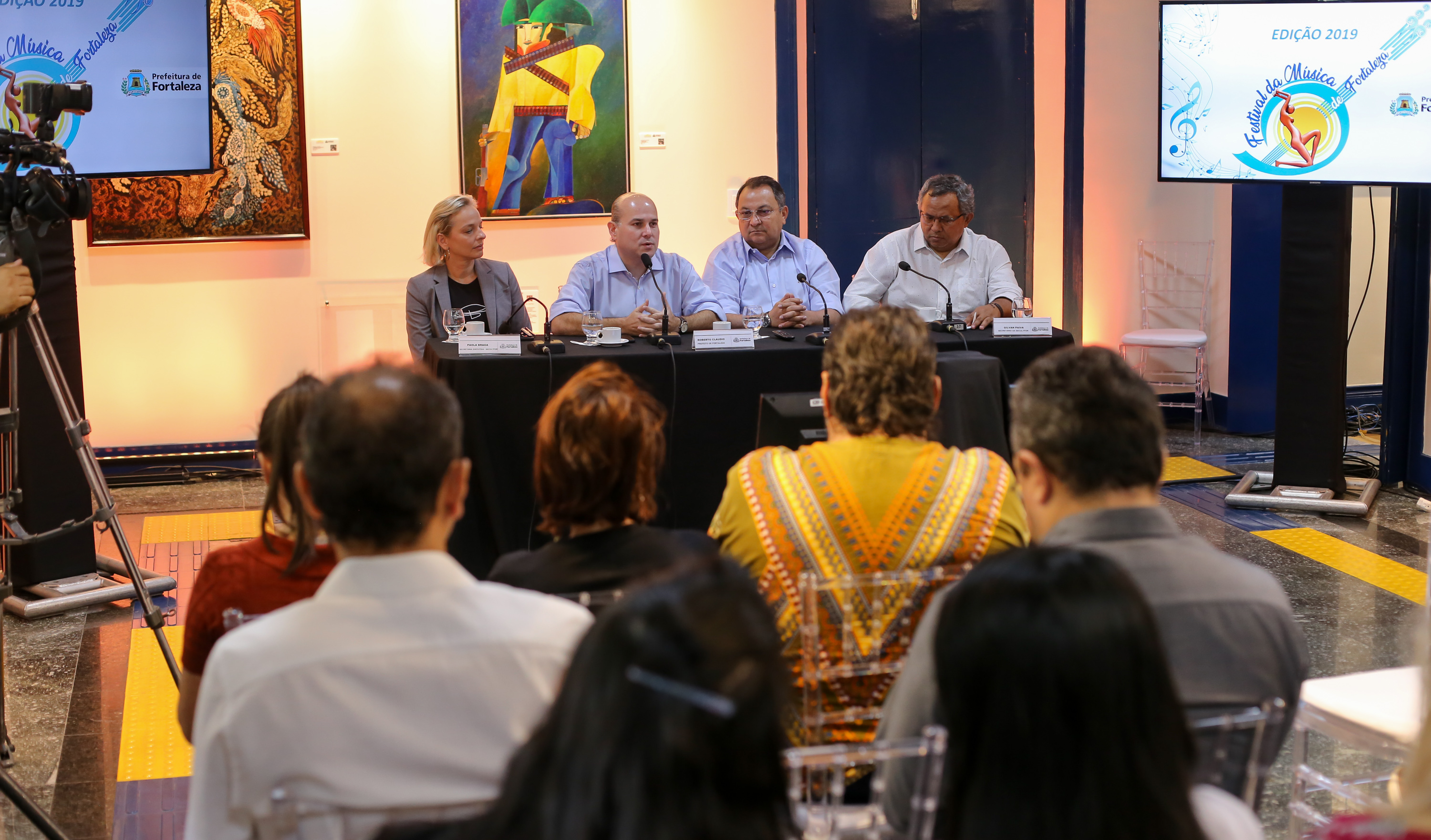 pessoas sentadas numa mesa de auditório